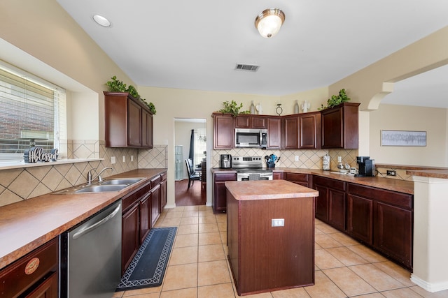 kitchen with appliances with stainless steel finishes, decorative backsplash, a sink, and plenty of natural light