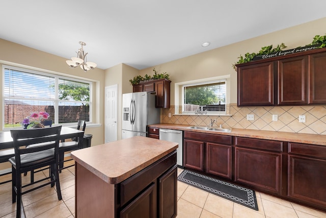 kitchen featuring a wealth of natural light, a sink, backsplash, a notable chandelier, and stainless steel appliances