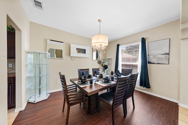 dining area featuring wood finished floors, baseboards, a chandelier, and visible vents