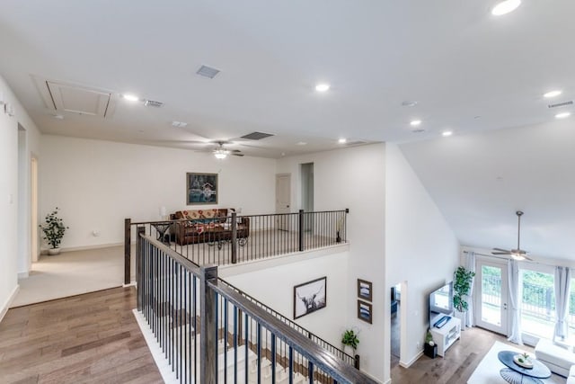corridor with visible vents, an upstairs landing, wood finished floors, and attic access