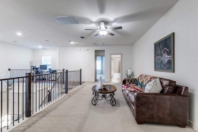 carpeted living room with visible vents, a ceiling fan, baseboards, and a wealth of natural light