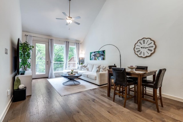 living area featuring baseboards, ceiling fan, wood finished floors, and high vaulted ceiling