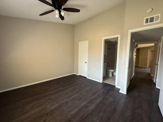 unfurnished bedroom with connected bathroom, dark wood finished floors, baseboards, lofted ceiling, and visible vents