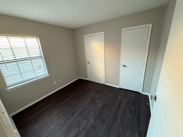 unfurnished bedroom with dark wood-type flooring and baseboards