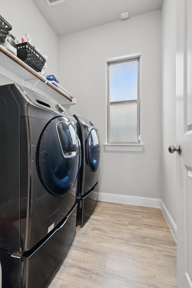 washroom featuring baseboards, laundry area, light wood-type flooring, and independent washer and dryer