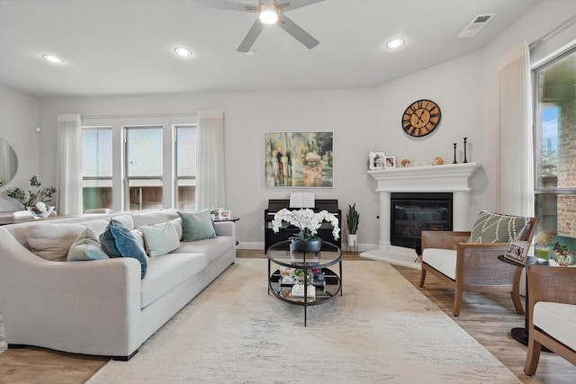 living area with recessed lighting, visible vents, a glass covered fireplace, and wood finished floors