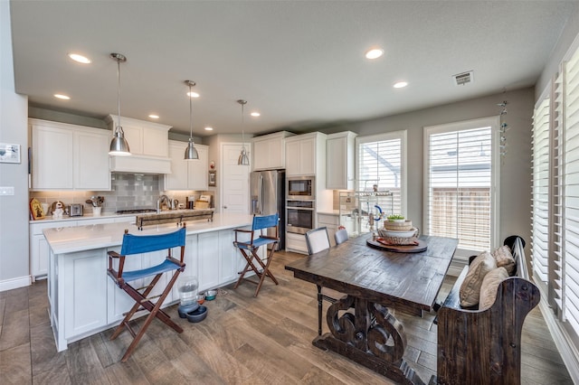kitchen featuring decorative backsplash, visible vents, light countertops, dark wood-style floors, and stainless steel appliances