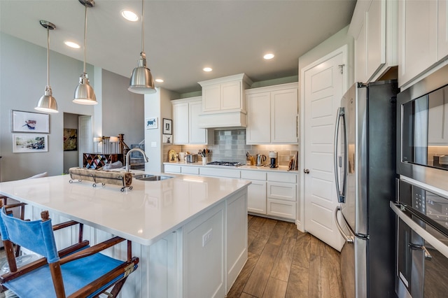 kitchen featuring appliances with stainless steel finishes, a breakfast bar, a sink, white cabinetry, and backsplash