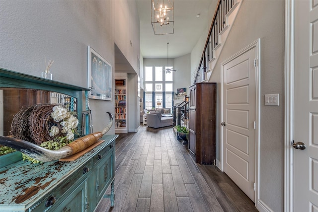 corridor with baseboards, dark wood-style flooring, a textured wall, and a chandelier