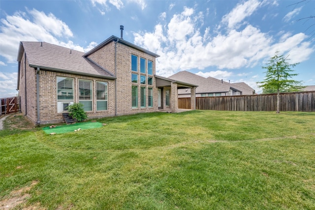 back of house featuring brick siding, a fenced backyard, and a yard