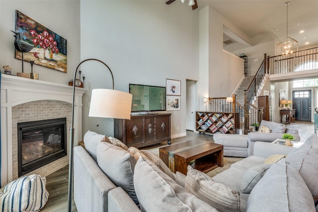 living area featuring a towering ceiling, wood finished floors, a fireplace, stairway, and a notable chandelier