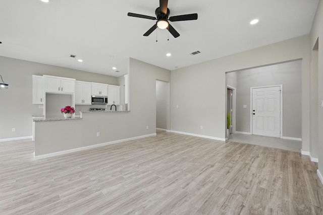 unfurnished living room with baseboards, ceiling fan, light wood finished floors, and visible vents
