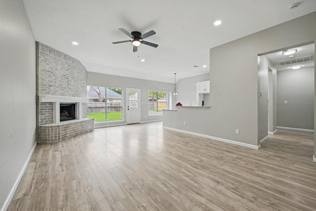 unfurnished living room featuring ceiling fan, visible vents, a fireplace, baseboards, and light wood-style flooring