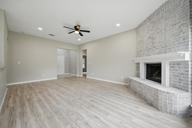 unfurnished living room featuring light wood finished floors, a fireplace, a ceiling fan, baseboards, and visible vents
