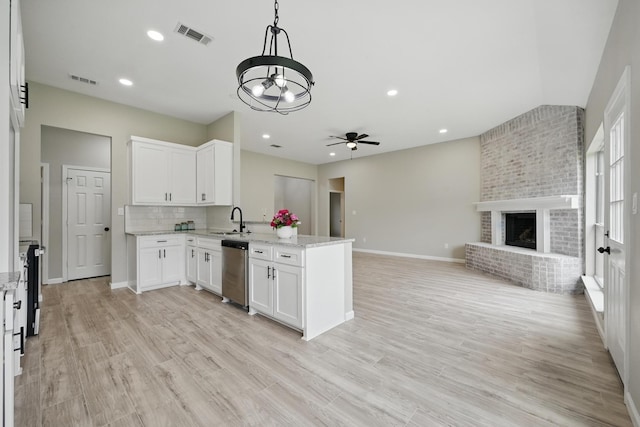 kitchen featuring a sink, a peninsula, open floor plan, white cabinetry, and stainless steel dishwasher