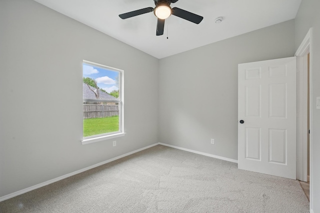 carpeted spare room featuring baseboards and ceiling fan