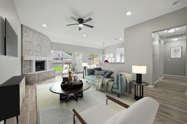 living area featuring ceiling fan, a brick fireplace, wood finished floors, baseboards, and recessed lighting