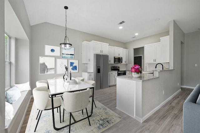 kitchen with white cabinets, a peninsula, appliances with stainless steel finishes, and visible vents