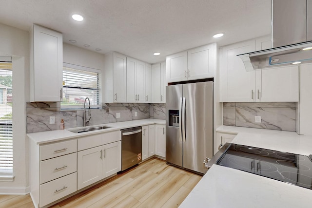 kitchen featuring white cabinets, appliances with stainless steel finishes, a sink, light wood-style floors, and light countertops