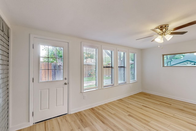 interior space with baseboards, a ceiling fan, and light wood-type flooring