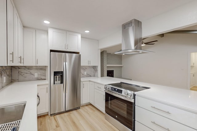 kitchen featuring island exhaust hood, light wood-style floors, white cabinetry, and stainless steel appliances