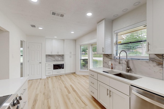 kitchen featuring visible vents, range, stainless steel dishwasher, a sink, and light countertops