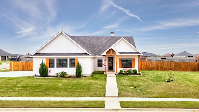 view of front of home with a shingled roof, a front lawn, and fence
