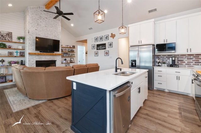 kitchen featuring stainless steel appliances, ceiling fan, a sink, and light wood finished floors