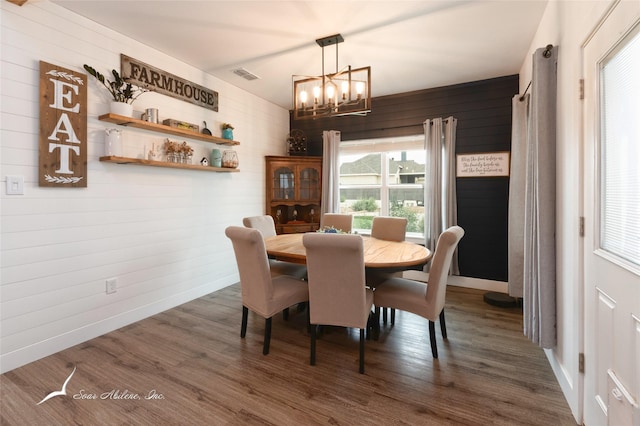 dining space featuring a notable chandelier, wood walls, and visible vents