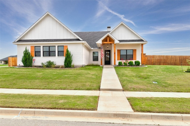 modern farmhouse featuring a shingled roof, board and batten siding, fence, and a front yard