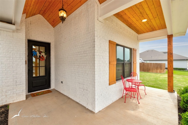 entrance to property featuring brick siding, a yard, and a porch