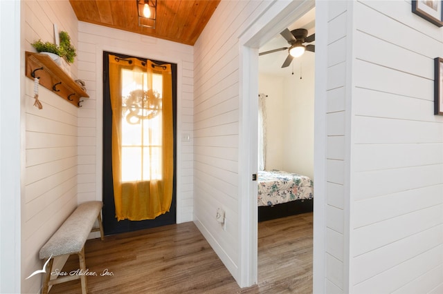 interior space featuring wooden walls, a ceiling fan, wood ceiling, and wood finished floors