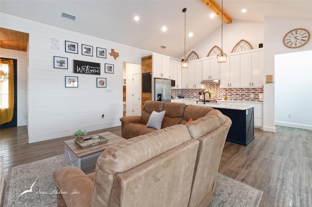 living area with visible vents, wood finished floors, beamed ceiling, baseboards, and high vaulted ceiling