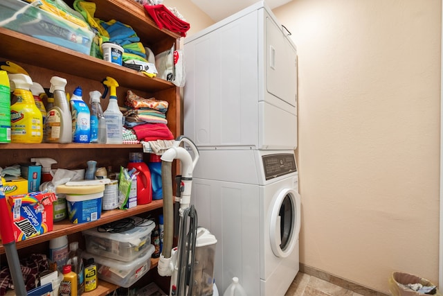 laundry area with baseboards, stacked washer / drying machine, and laundry area