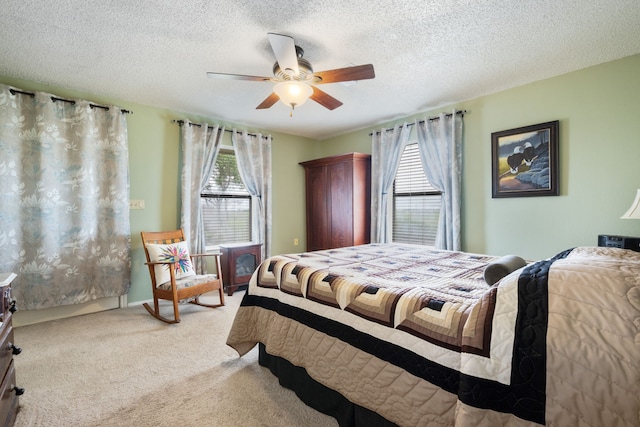 bedroom with ceiling fan, light carpet, and a textured ceiling