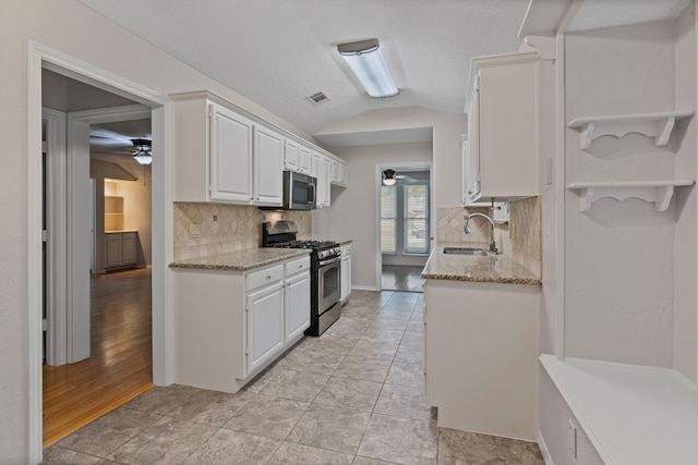 kitchen featuring a ceiling fan, a sink, appliances with stainless steel finishes, and lofted ceiling
