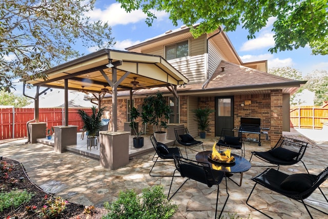 view of patio with a fenced backyard, a ceiling fan, and a fire pit