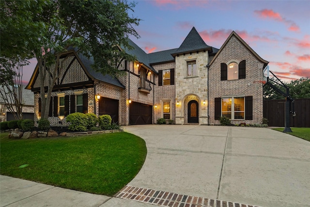 french provincial home featuring concrete driveway, a balcony, stone siding, and a front lawn