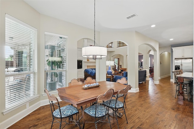dining area with visible vents, arched walkways, dark wood finished floors, and baseboards