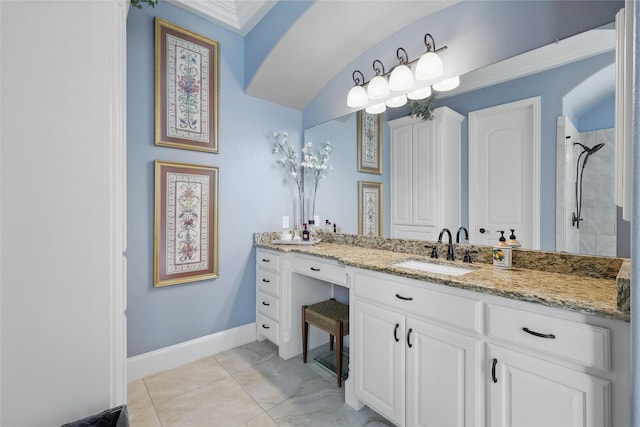 full bath featuring baseboards, a tile shower, and vanity
