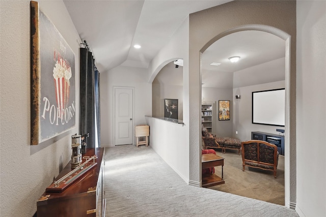 corridor featuring carpet flooring, arched walkways, baseboards, and lofted ceiling