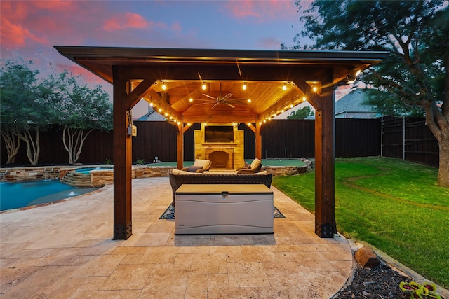 view of patio with a fenced backyard, a gazebo, a pool with connected hot tub, and an outdoor stone fireplace