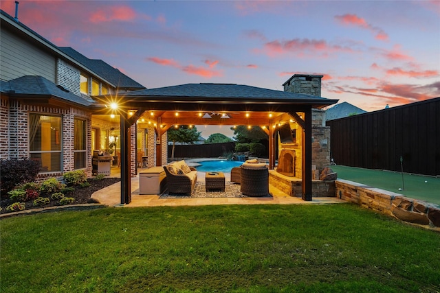 patio terrace at dusk with a lawn, a gazebo, and a fenced backyard