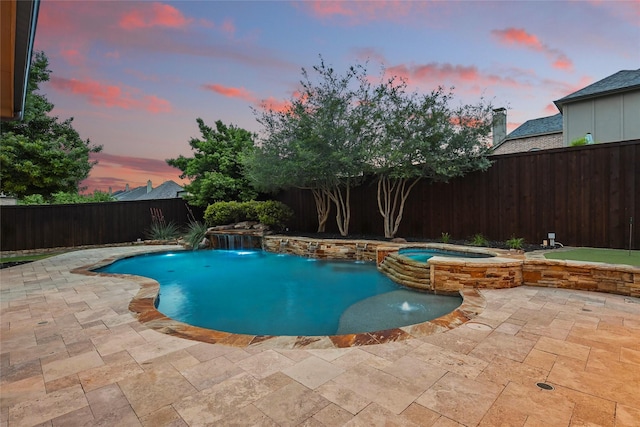 pool at dusk featuring a patio, a fenced backyard, and a pool with connected hot tub