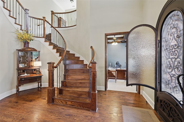 entrance foyer featuring a high ceiling, stairs, a ceiling fan, baseboards, and wood finished floors