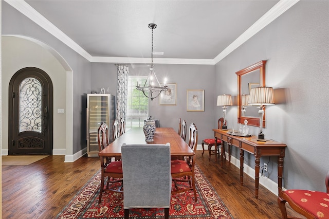 dining room with crown molding, wood finished floors, baseboards, arched walkways, and a notable chandelier