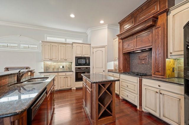 kitchen with a sink, a center island with sink, cream cabinets, and black appliances