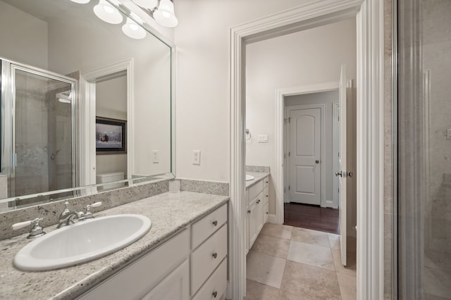 bathroom with toilet, a shower stall, tile patterned flooring, and vanity