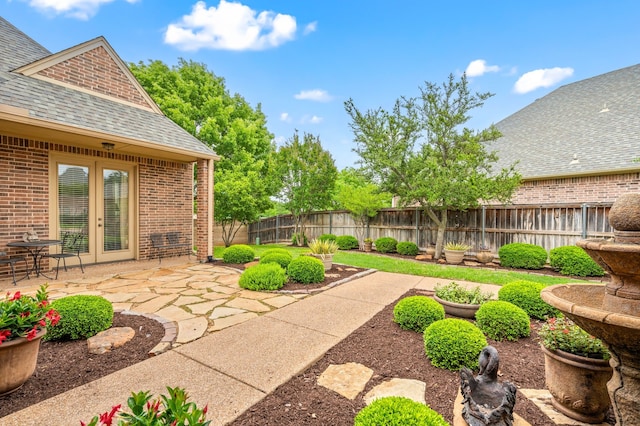 view of yard with a patio, a fenced backyard, and french doors