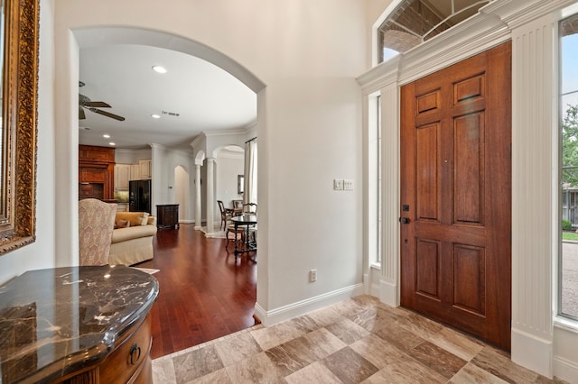 foyer entrance with arched walkways, ceiling fan, visible vents, and baseboards